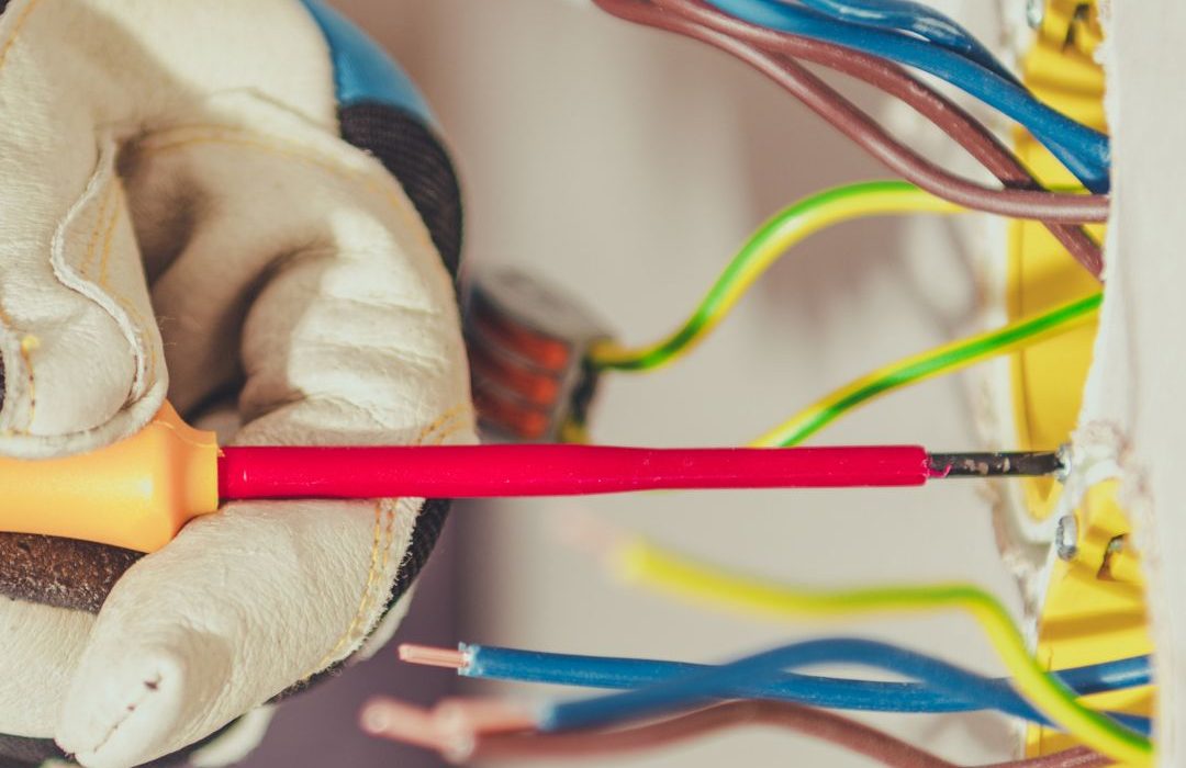 Técnico realizando instalación eléctrica con guantes de seguridad y herramientas aisladas para prevenir riesgos eléctricos